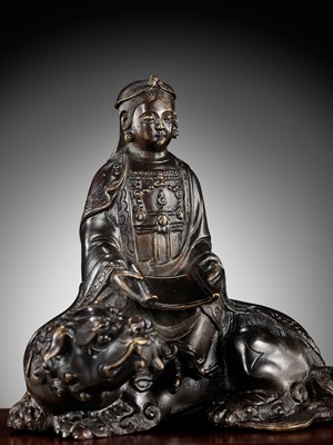 Lot 661 - A BRONZE FIGURE OF WENSHU (MANJUSHRI) ON A LION, LATE MING TO EARLY QING DYNASTY