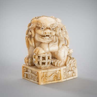 Lot 1561 - A FINE IVORY NETSUKE OF A SHISHI WITH A BALL