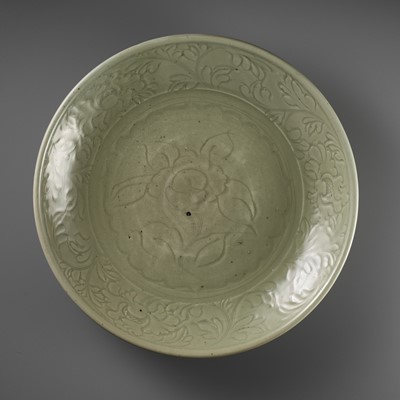 Lot 174 - A LARGE AND FINELY CARVED ‘PEONY’ LONGQUAN CELADON CHARGER, MING DYNASTY