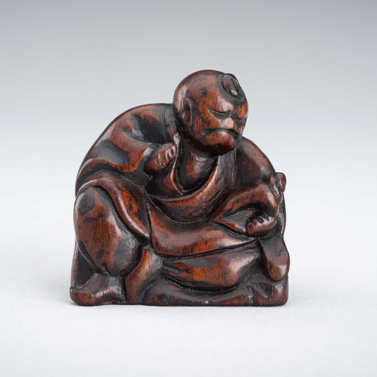 A WOOD NETSUKE OF A YAMABUSHI MONK WITH CONCH