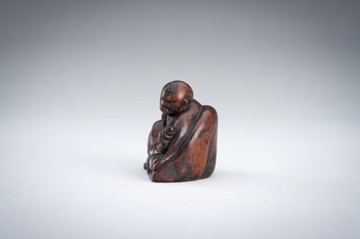 A WOOD NETSUKE OF A YAMABUSHI MONK WITH CONCH