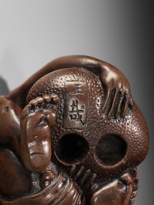 Lot 232 - GYOKUSAI: A FINE WOOD NETSUKE OF A BLIND MASSEUR LIFTING A CHIKARAISHI