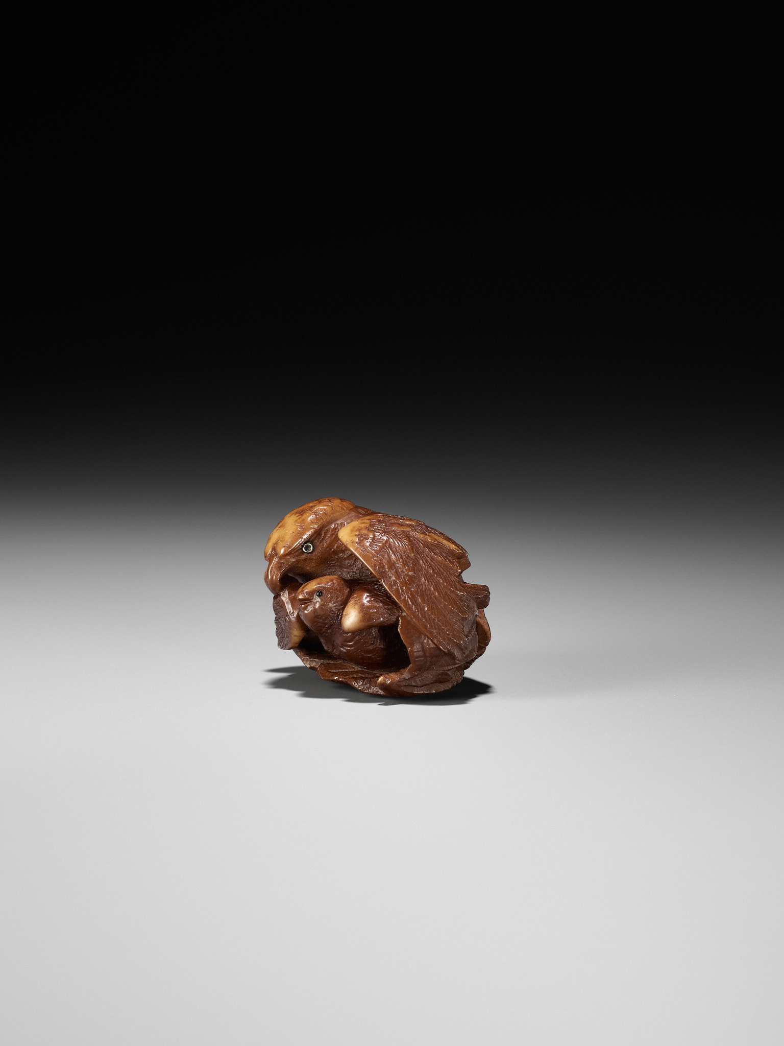 Lot 467 - A COROZO NUT NETSUKE OF A HAWK AND YOUNG