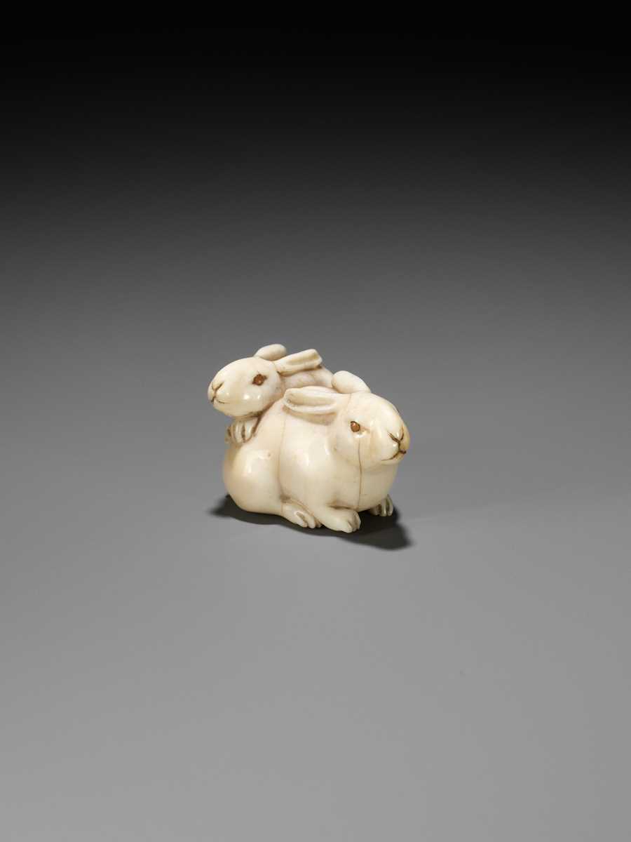 Lot 131 - A FINE IVORY NETSUKE DEPICTING TWO RABBITS