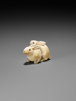 Lot 131 - A FINE IVORY NETSUKE DEPICTING TWO RABBITS WITH CORAL-INLAID EYES
