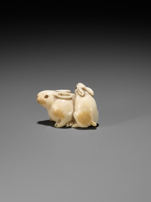 Lot 131 - A FINE IVORY NETSUKE DEPICTING TWO RABBITS WITH CORAL-INLAID EYES