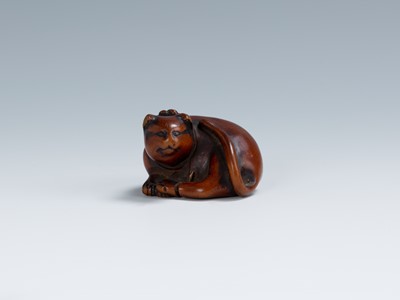 Lot 396 - AN OLD WOOD NETSUKE OF A RECUMBENT CAT