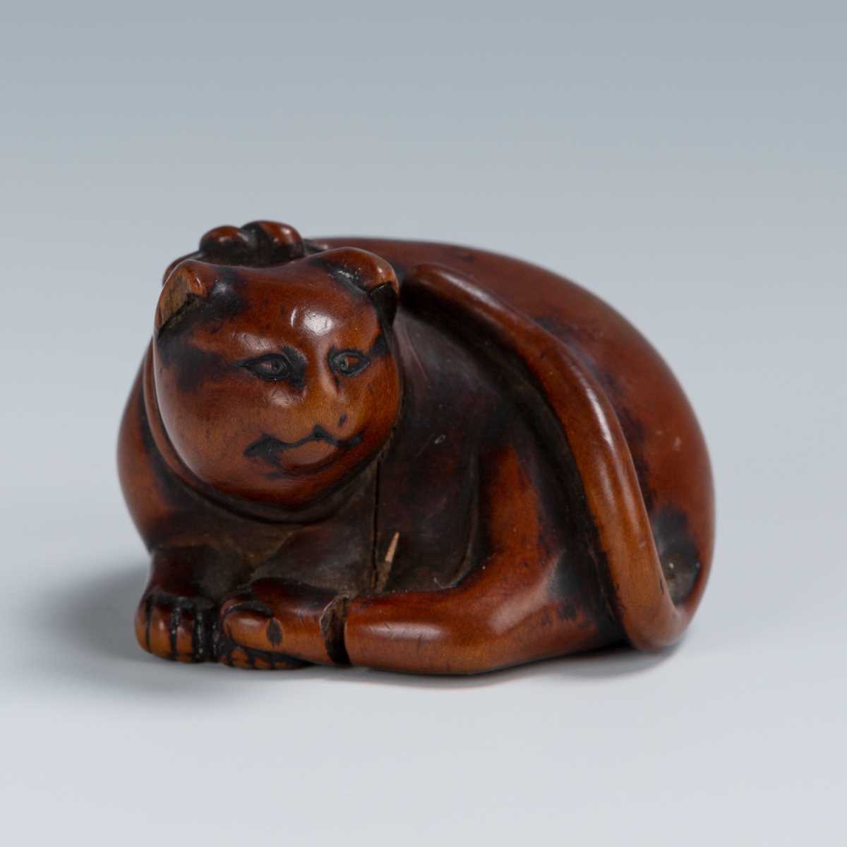 Lot 396 - AN OLD WOOD NETSUKE OF A RECUMBENT CAT