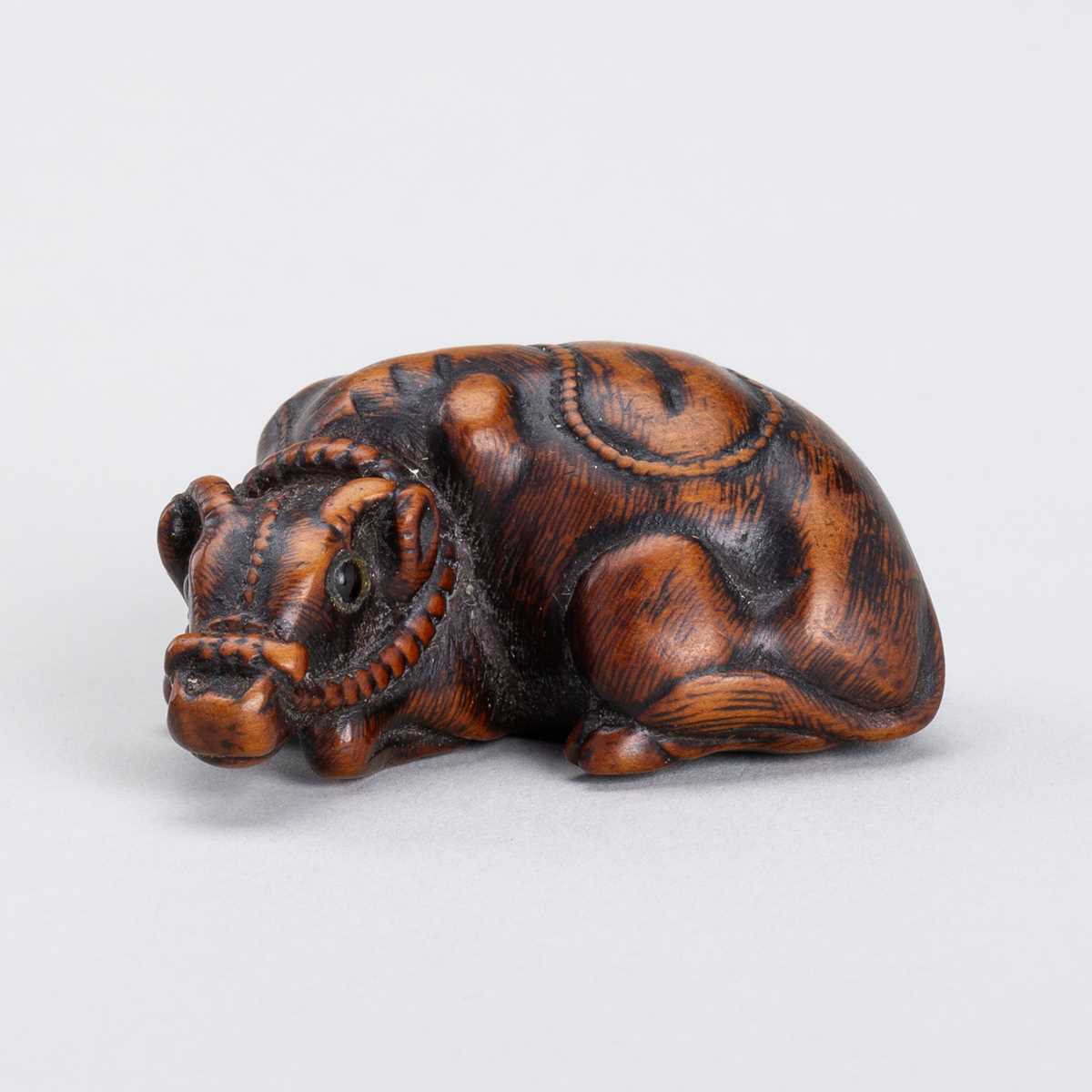 Lot 328 - A WOOD NETSUKE OF A RECUMBENT OX