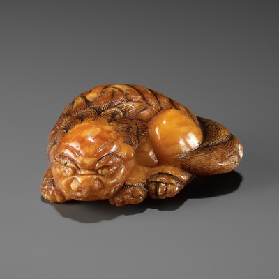 Lot 283 - A VERY RARE CLOUDY AMBER NETSUKE OF A RECUMBENT SHISHI