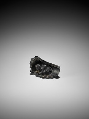 Lot 300 - A RARE HORN NETSUKE OF A PUPPY NESTLED WITHIN A ROOF TILE, ATTRIBUTED TO HORAKU