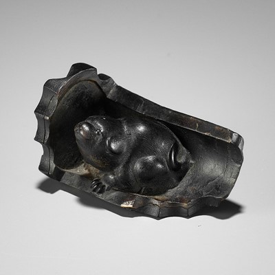 Lot 300 - A RARE HORN NETSUKE OF A PUPPY NESTLED WITHIN A ROOF TILE, ATTRIBUTED TO HORAKU