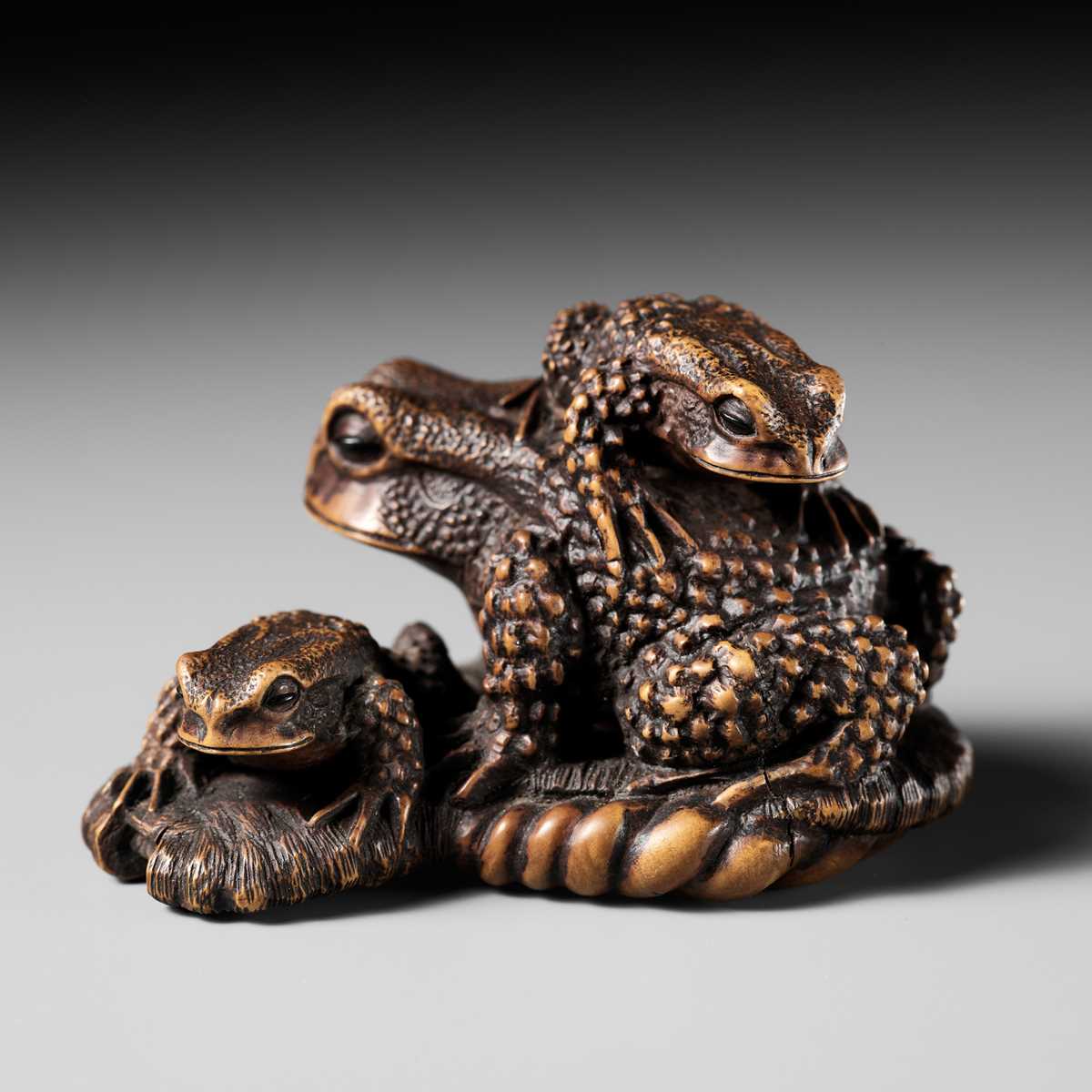 Lot 386 - MASANAO: A FINE WOOD NETSUKE OKIMONO OF A TOAD WITH TWO YOUNG ON WARAJI