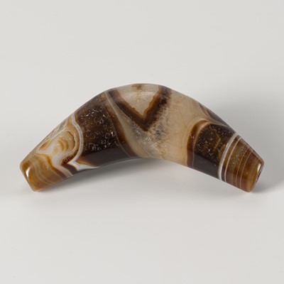 Lot 1091 - A BOW-SHAPED HIMALAYAN BANDED AGATE BEAD, 19TH CENTURY OR EARLIER