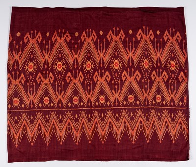 Lot 987 - A KHMER TRIBAL RED-GROUND SILK IKAT TEXTILE, 1900s