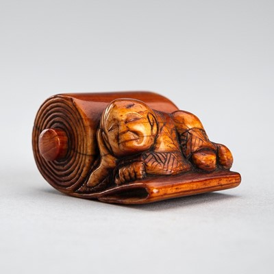 Lot 1269 - AN IVORY NETSUKE OF A MAN SLEEPING ON A LARGE SCROLL, EDO PERIOD