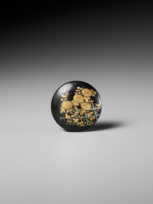 A LACQUERED WOOD MANJU NETSUKE DEPICTING CHRYSANTHEMUMS BY A FENCE