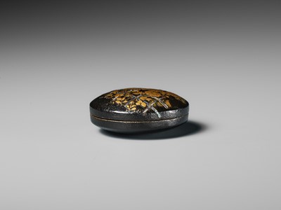 Lot 26 - A LACQUERED WOOD MANJU NETSUKE DEPICTING CHRYSANTHEMUMS BY A FENCE