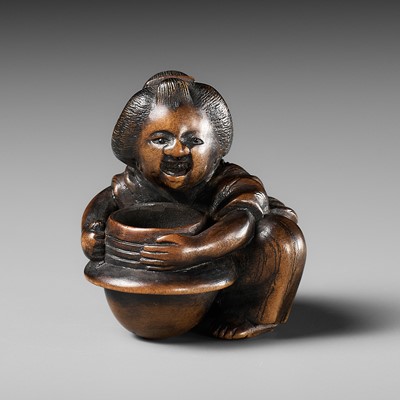 Lot 474 - A WOOD NETSUKE OF A WOMAN WASHING A TETSUNABE (IRON POT) FOR COOKING RICE