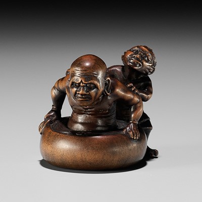 Lot 156 - MINKOKU: A FINE AND HUMOROUS WOOD NETSUKE OF AN ONI BATHING A RAKAN