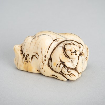 AN IVORY NETSUKE OF A MAN RESTING ON A ROCK, EDO PERIOD