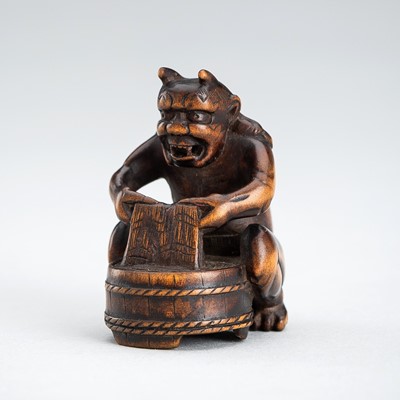 Lot 537 - A WOOD NETSUKE OF AN ONI DOING LAUNDRY