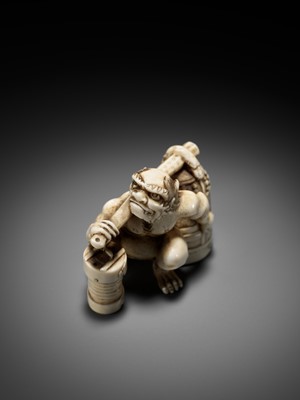 Lot 500 - RYOZAN: AN AMUSING IVORY NETSUKE OF AN ONI CARRYING A BONSHO AND CHOCHIN, CHOCHIN NI TSURIGANE