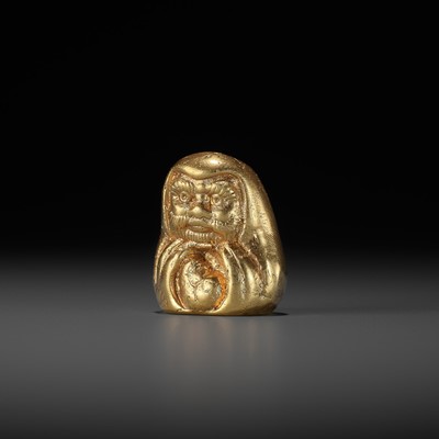 A GILT METAL NETSUKE PORTRAYING A DARUMA DOLL