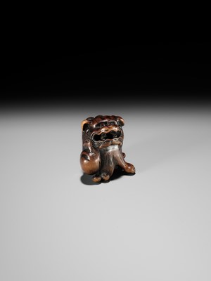 A WOOD NETSUKE OF A SHISHI SCRATCHING ITS JOWL, ATTRIBUTED TO RISUKE GARAKU