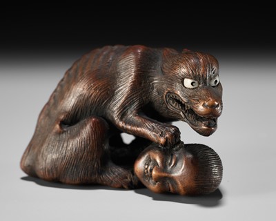 Lot 125 - SHIGEKAZU: A FINE WOOD NETSUKE OF AN EMACIATED WOLF WITH A SEVERED HEAD