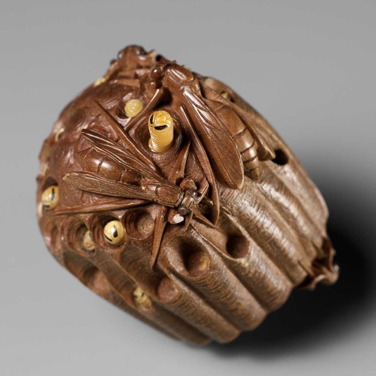 Lot 105 - TADAKAZU: A FINE WOOD NETSUKE OF A WASP NEST WITH MOVABLE LARVAE