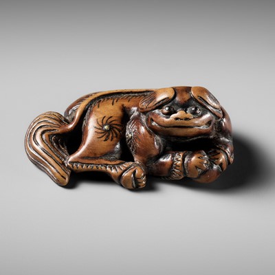 Lot 417 - AN UNUSUAL AND EARLY WOOD NETSUKE OF A RECUMBENT SHISHI