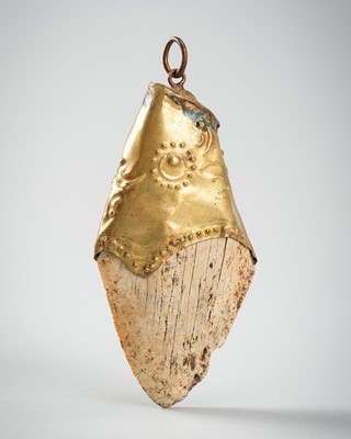 Lot 1161 - A JAVANESE SHARK’S TOOTH PENDANT SET IN GILT METAL, c. 10TH – 12th CENTURY