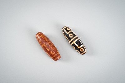 Lot 1517 - A LOT WITH TWO TIBETAN AGATE DZI BEADS, 18TH CENTURY OR EARLIER