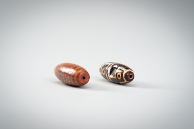Lot 1517 - A LOT WITH TWO TIBETAN AGATE DZI BEADS, 18TH CENTURY OR EARLIER