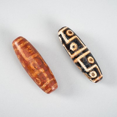 Lot 1517 - A LOT WITH TWO TIBETAN AGATE DZI BEADS, 18TH CENTURY OR EARLIER