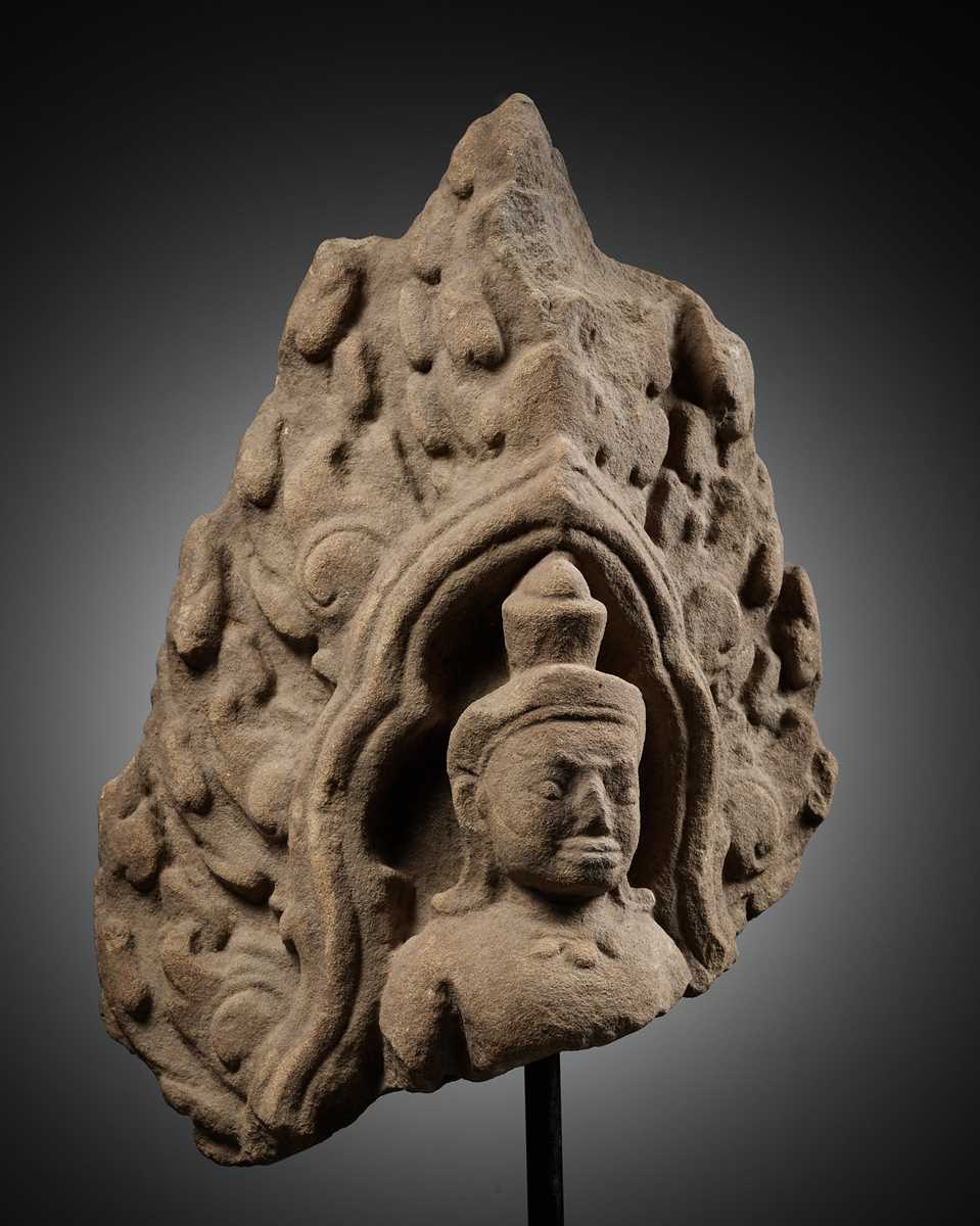 Lot 979 - A SANDSTONE ANTEFIX OF A MALE DEITY, ANGKOR