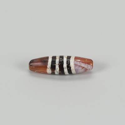 Lot 1512 - A TIBETAN AGATE ‘CHUNG DZI’ BEAD WITH LINEAR DECORATION, c. 500-1000 CE