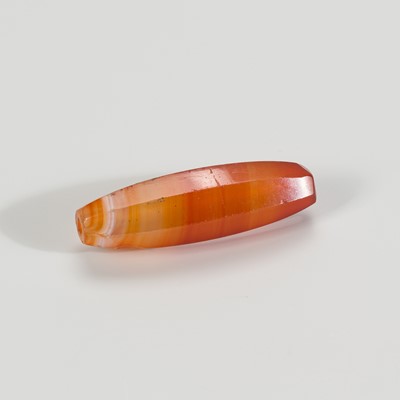 Lot 1200 - A CYLINDRICAL BANDED AGATE BEAD, 19TH CENTURY OR EARLIER