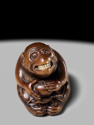 Lot 144 - AN AMUSING WOOD NETSUKE OF A MONKEY EATING A PERSIMMON