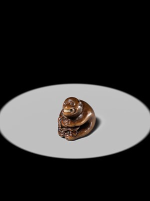 Lot 144 - AN AMUSING WOOD NETSUKE OF A MONKEY EATING A PERSIMMON