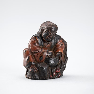 Lot 670 - A LACQUERED PRESSED HORN NETSUKE OF HANASAKA-JIJI WITH A BASKET OF ASHES