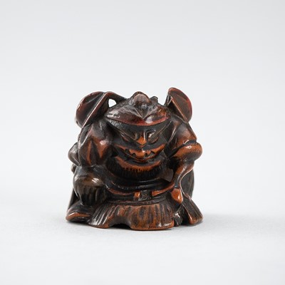 A WOOD NETSUKE OF SHOKI TRAPPING AN ONI