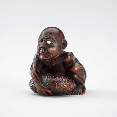 GYOKKEI: A WOOD NETSUKE OF A BLIND MAN LIFTING A CHIKARAISHI