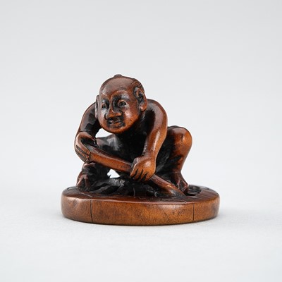 Lot 546 - HOKEI: A WOOD NETSUKE OF A MAN FIXING A WHEEL