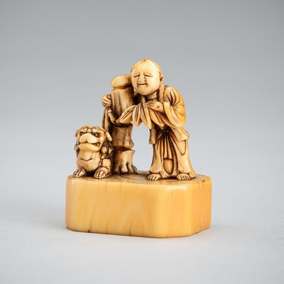 Lot 549 - AN IVORY NETSUKE OF A BOY WITH SHISHI