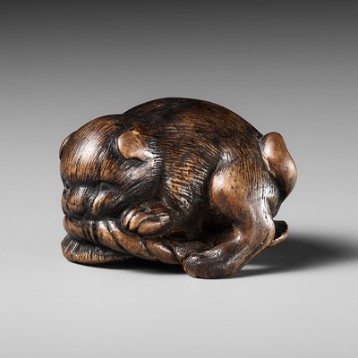 Lot 458 - KOKEI: A WOOD NETSUKE OF A PUPPY PLAYING WITH A SANDAL