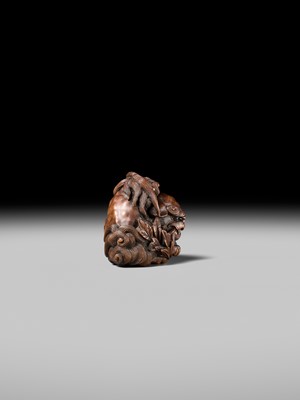 Lot 184 - SUKETADA: A SUPERB WOOD NETSUKE OF A SHISHI WITH PEONY