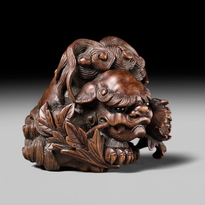 Lot 184 - SUKETADA: A SUPERB WOOD NETSUKE OF A SHISHI WITH PEONY