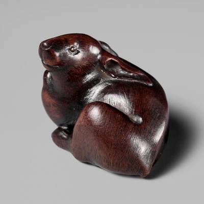 Lot 146 - MASANOBU: A NAGOYA SCHOOL WOOD NETSUKE OF A HARE WITH AMBER EYES